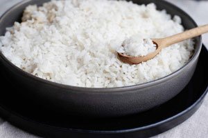 Идеальный белый рис в металлической кастрюле с деревянной ложкой, полной вареного белого риса
